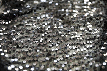 defocused black and silver knitted fabric with sequins and folds texture background	