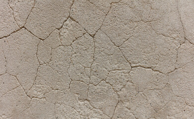 Destroy dry sandstone with time in the form of a network of uneven cracks of different depths of beige color. background texture