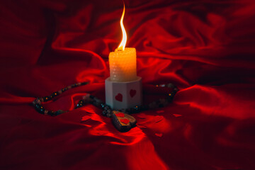 burning candle, a symbol of the moon, an amulet lying on a red natural background. pagan wiccan,...