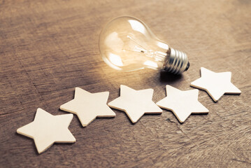 Wooden five stars with glowing light bulb, success, and idea from the excellent feedback, good...