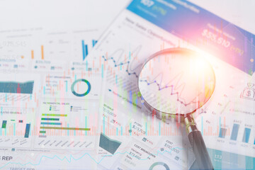 Business analytics and statistics. Businessman study report using a magnifying glass.searching and finding business solution marketing or finding strategy for business