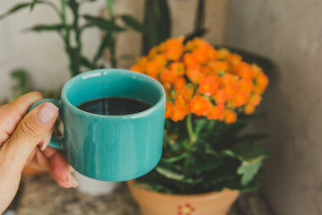 mão segurando uma xícara de café com flores