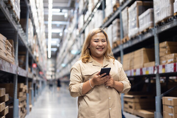 Female customer. Plus size female warehouse worker inspecting box of products by smart phone while working in large warehouse