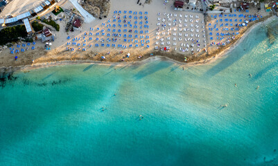 Beach umbrellas in a row at fig tree bay beach Protaras Cyprus. Summer vacations holiday resort golden sand