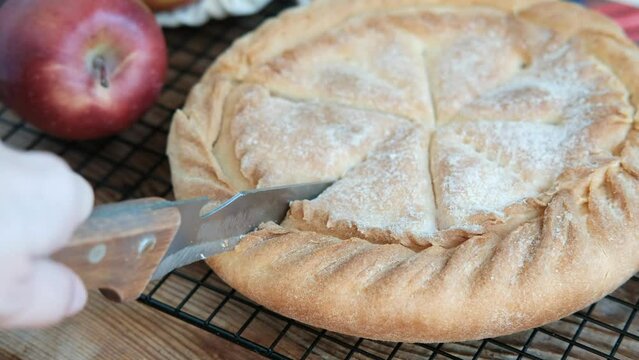 cut apple pie with knife on wooden background,close up