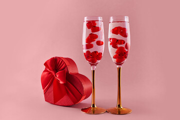 Happy Valentine's Day. Two glasses of champagne wine with red hearts in them. Pink background.