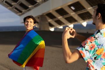 Gay couple having fun outside. Happy couple making a heart sign with their hands..