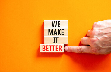 We make it better symbol. Concept words We make it better on wooden blocks. Beautiful orange table orange background. Businessman hand. Business we make it better concept. Copy space.