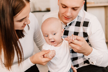 Little boy happy funny surprised cute child baby playing with parents, sitting on knees. Playful shocked toddler with big eyes having fun, making faces grimaces. Happy childhood, family concept
