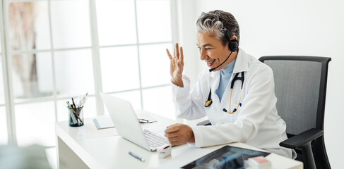 Virtual doctor’s appointment: Friendly female health professional waving to a patient over a...