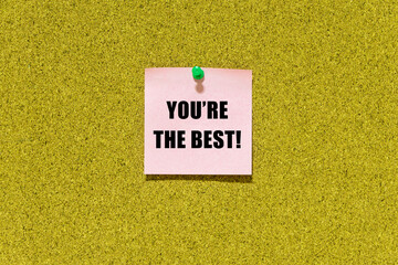 "You're the best" message on pink post-it paper on cork board. This text can be used in business concept about encouraging, motivating and inspiring people.
