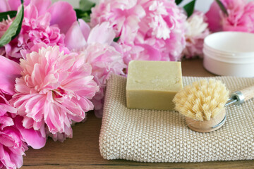 Obraz na płótnie Canvas Beauty composition. Handmade soap, moisturizer and towel.A scene with pink peony flowers, and petals on white background. Spa, feminine care products. Hygiene concept photo.Flat lay, top view.
