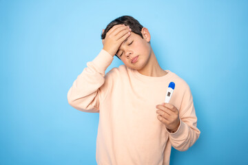boy feeling bad with thermometer over blue background