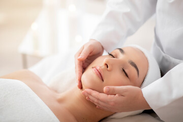 Obraz na płótnie Canvas Closeup Shot Of Young Indian Female Having Face Massage In Spa Salon