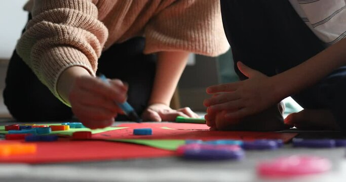 Video animation of woman teaching to draw, paint little boy on special color paper by markers and crayons on the floor
