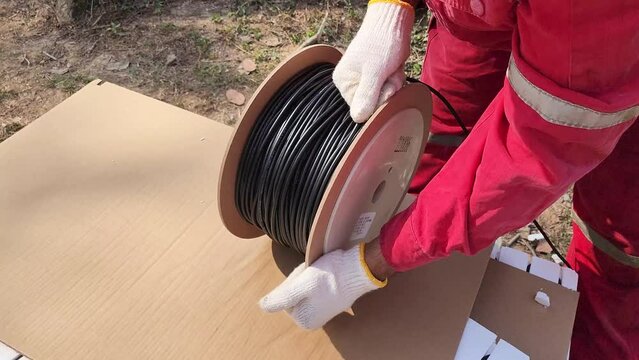 Action of a worker is rolling the electrical wire cable into the reel. Industrial working scene, 4k footage.