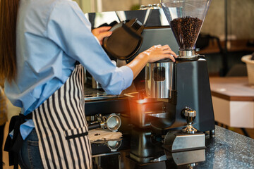 makes Americano coffee from the coffee machine. The shop owner hands holding the coffee machine teaches staff how to learn to be a barita.