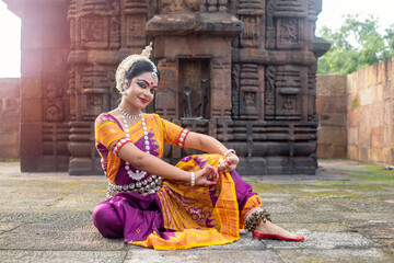 Indian Classical odissi dancer posing in front of temple