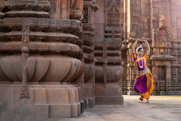 Indian classical dancer in traditional dress and posing in front of temple. Classical indian temple...