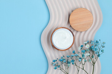 Cosmetic cream jar on concrete decoration wave with field flowers, minimalistic style concept on...