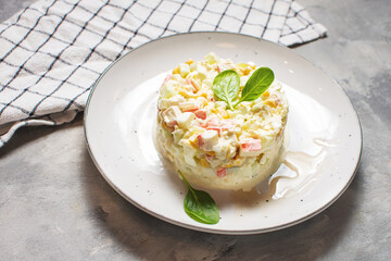 Traditional Russian salad with corn, crab meat and mayonnaise on concrete background