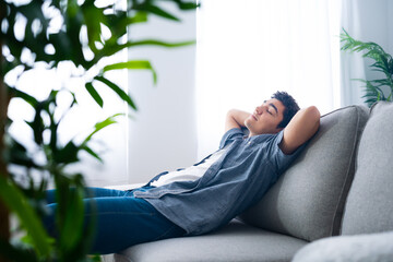 Hispanic teenager boy lying and relaxing on couch. - Powered by Adobe