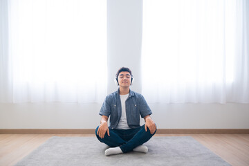 Hispanic teenager boy listening relaxing music sitting on the floor. Meditation and mindfulness...