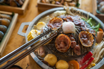 Closeup of grill with deliciouse seafood, shrimp, crab, mussle, pork sausage and vegetable on wood table in BBQ grill restaurant from thailand