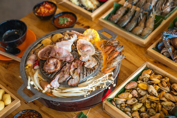 Wood Table with deliciouse seafood, shrimp, crab, mussle, pork saussage and vegetable in bbq grill restaurant from thailand