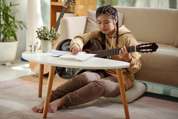 Teenage girl learning how to play guitar and trying to play various chords