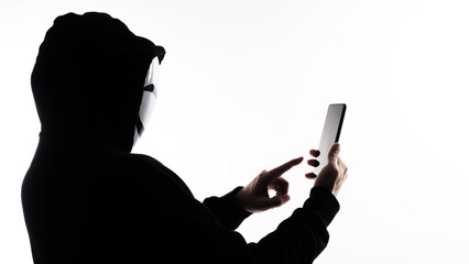 Hacker Anonymous and face mask with smartphone in hand. Man in black hood shirt holding and using...