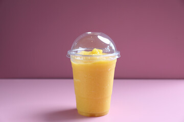 Mango smoothie milk shake with take out glass isolated on pink background