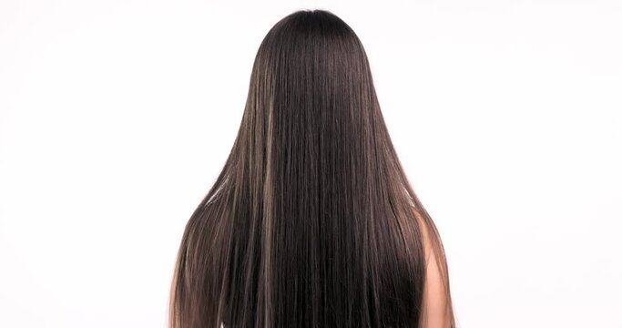 Woman moves long hair. Rear view. Girl shakes long straight hair. Slow motion footage. Rear view. 4k. Female model is fluttering hair.