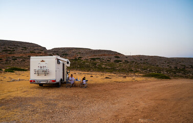Family traveling by motorhome are eating breakfast on Tendopoula beach, Crete, Greece.