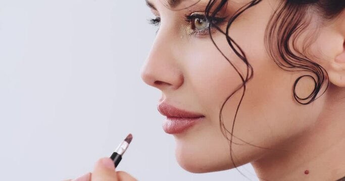 Stylist makeup artist  applies lipstick on the lips of the fashion model. Stylist making makeup applying lipstick on a lip with lipstick pencil. Preparing to the photossesion. Professional makeup.