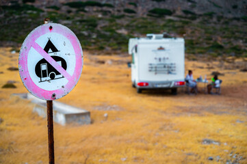 No camping sign with motorhome parked in the background.