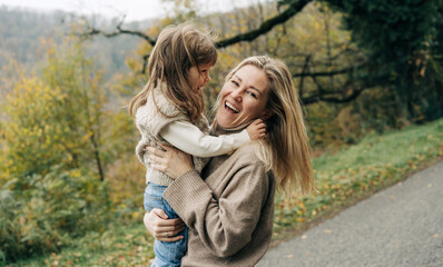 Happy cheerful mom and little daughter play on a walk.
