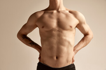 Cropped image of male relief body, breast, belly and hands over grey background. Model posing in underwear. Concept of men's health and beauty, body and skin care, fitness. Body art