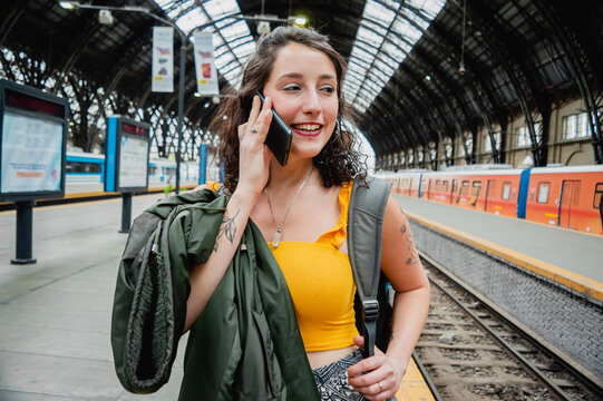 portrait of young latin traveler woman on a phone call, smiling y listening carefully.
