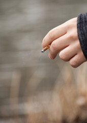 a smoldering cigarette in a man's hand