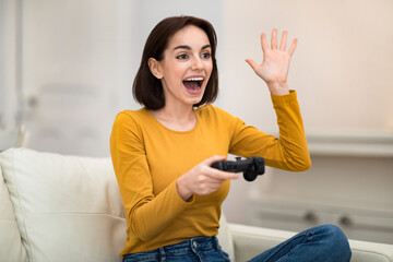 Happy young woman playing video games at home © Prostock-studio