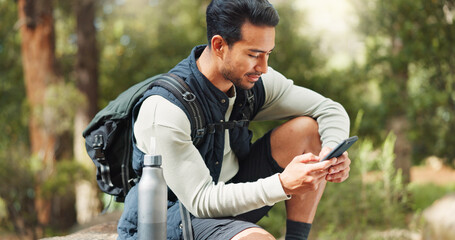 Nature hiking man, typing phone and sitting on rock for rest, break or relax with backpack outdoor....