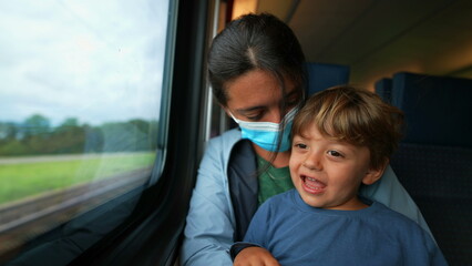 Parent and child traveling by train during coronavirus pandemic mother wearing face mask