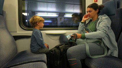 Mother and child traveling by train together little boy listens to mom on transportation