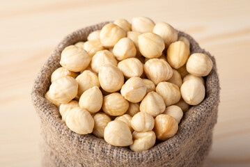 Fototapeta na wymiar Small linen bag with hazelnuts. Close up of peeled hazelnuts in linen sack
