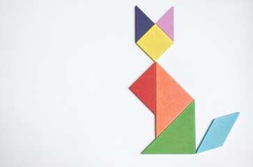 color tangram puzzle in sitting cat shape on wood background