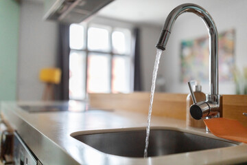 Close up shot of modern kitchen faucet with water running from tap