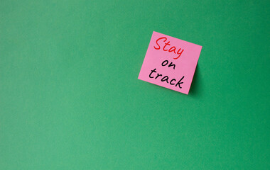 Stay on track symbol. Concept words words Stay on track on pink steaky note. Beautiful green background. Business and Stay on track concept. Copy space.