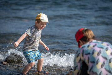 Niño saltando y jugando con piedras y agua a orillas de un lago