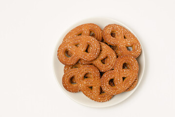 Plate with shaped rye cookies or pretzels  with crystal sugar isolated on white background top view
